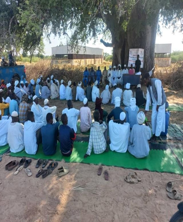 A large community gathering held under the trees